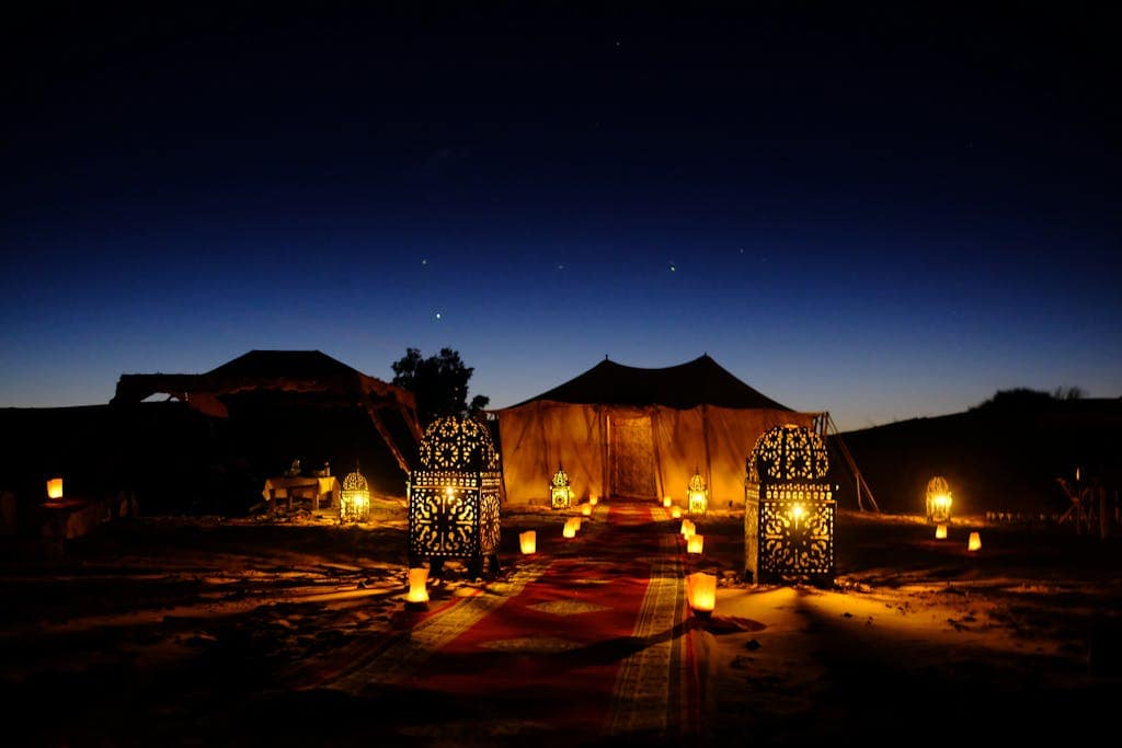 Illuminated tents with lanterns at twilight in Egypt's desert, creating a magical ambiance.